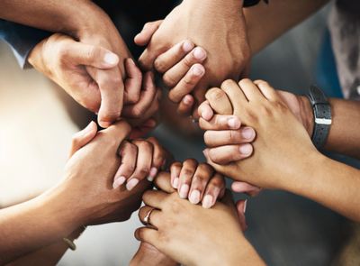 Multiple hands joined together in a circle symbolizing unity and support.