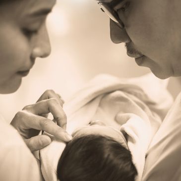 Parents lovingly gaze at their newborn baby wrapped in a blanket.