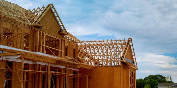 Partially constructed wooden house frame under a cloudy sky.