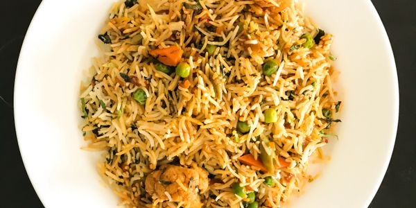 A bowl of vegetable fried rice with peas and carrots.