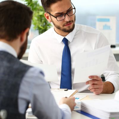 Two businessmen reviewing documents in an office setting.