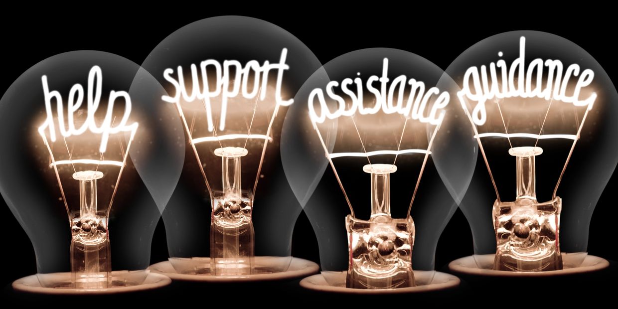 Light bulbs glowing with words help, support, assistance, guidance inside.