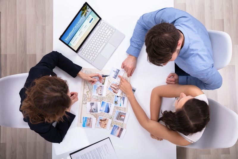 Female Travel Agent Giving Information To A Young Couple For Vacation Package