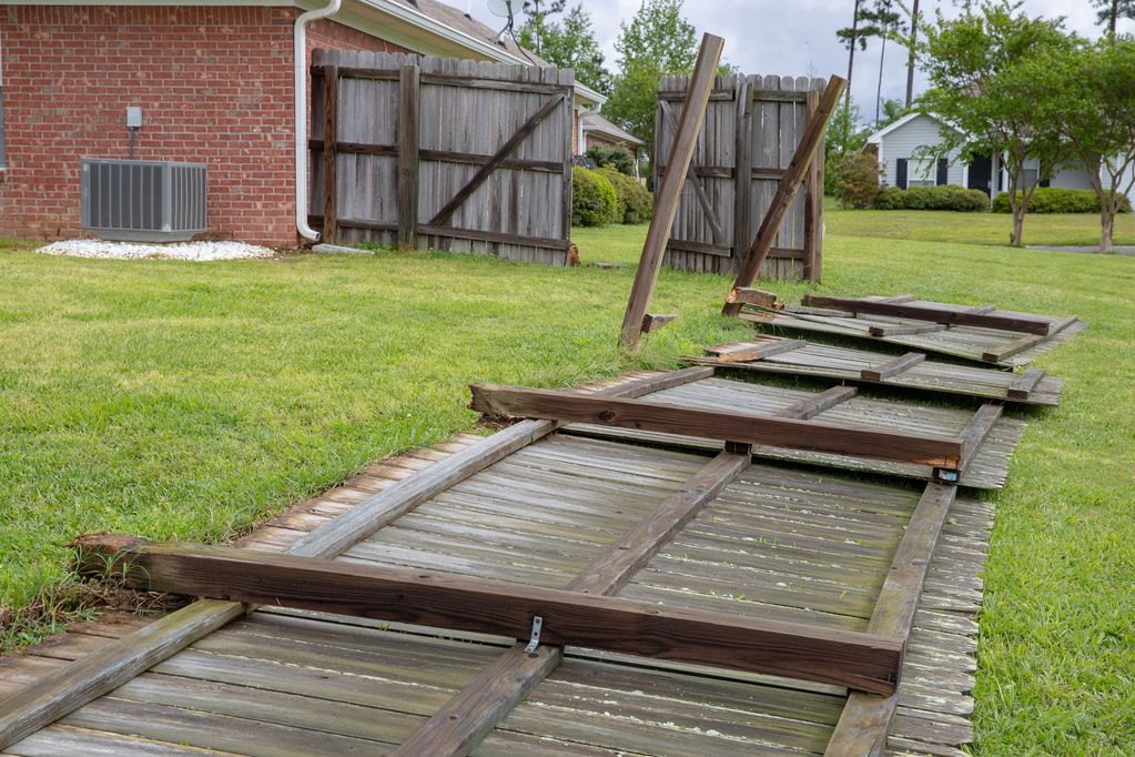 A broken wooden fence lying on the grass in a residential area. Demolition Services in Kingsport