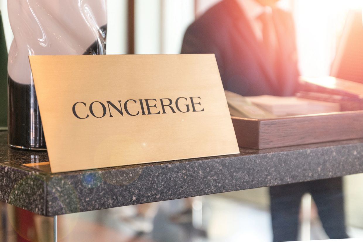 Gold concierge sign on a marble counter with a blurred person in the background.