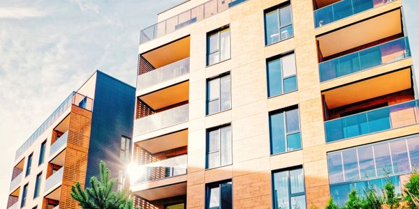 Modern apartment buildings with glass balconies under a bright sky.