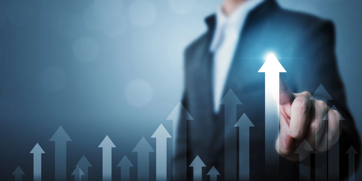 Businessman pointing at an upward arrow symbolizing growth.