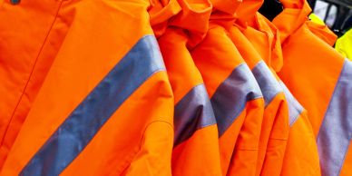 Row of orange safety jackets with reflective stripes.