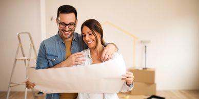 Happy couple reviewing home renovation plans in a room under renovation. contractors maine