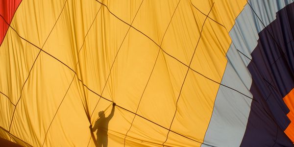 Silhouette of a person inside a colorful hot air balloon being inflated.