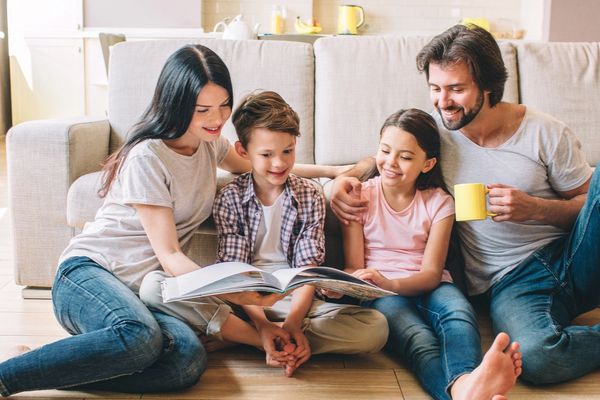 Family reading together happily on the floor.
