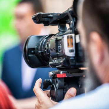 A videographer filming a person with a professional camera.