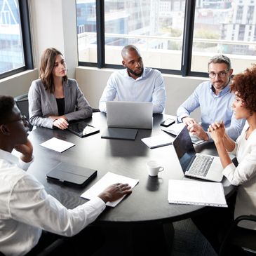 A diverse group of professionals engaged in a serious business meeting around a table.