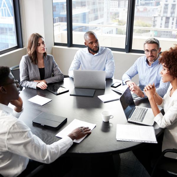 A diverse group of professionals engaged in a serious business meeting around a table.