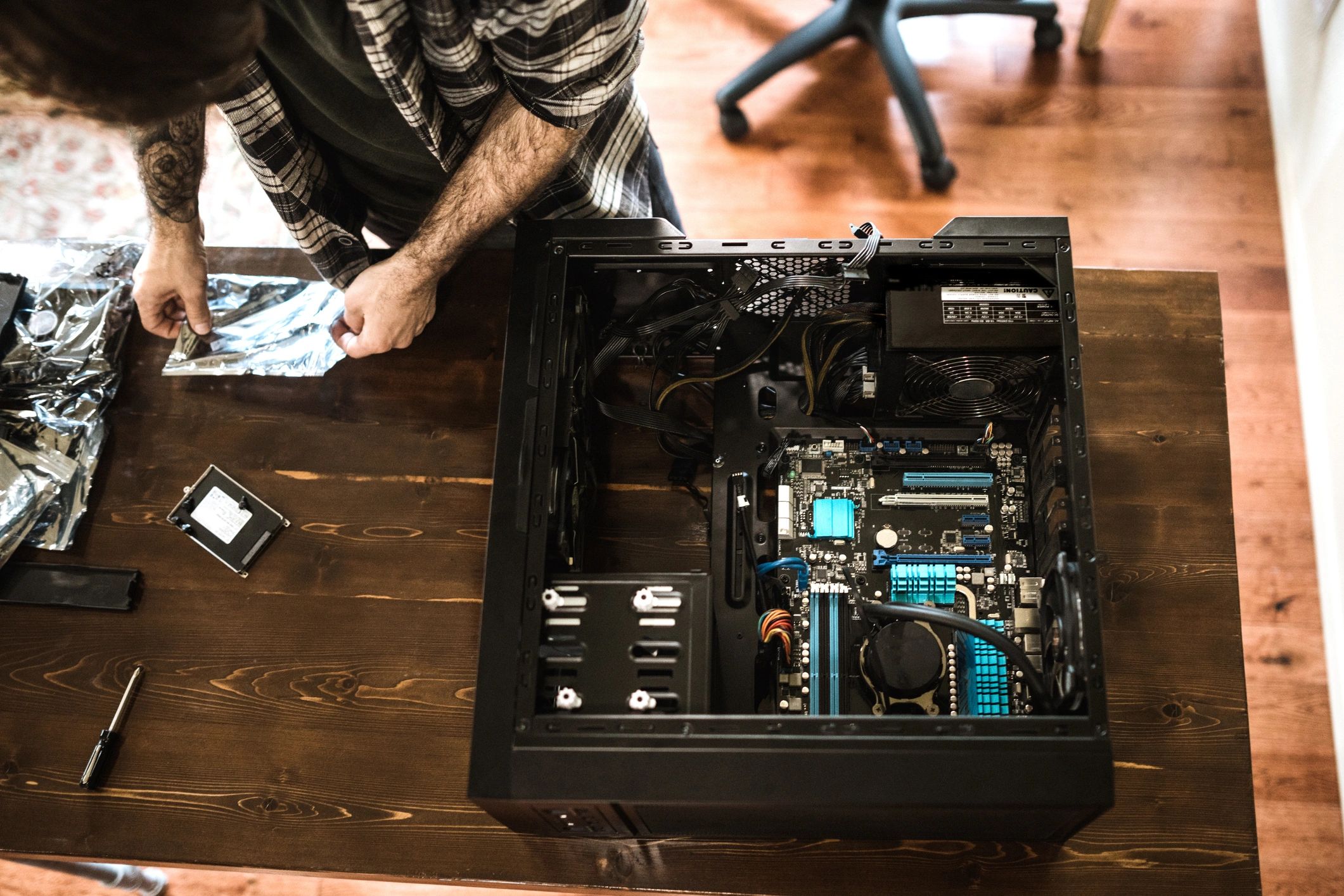 Person assembling a desktop computer on a wooden table.