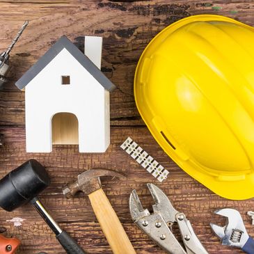 Construction tools and a yellow safety helmet on a wooden surface.