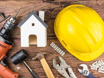 Construction tools with a yellow helmet and house model.