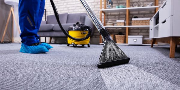 Professional carpet cleaning in a living room with a vacuum extractor.