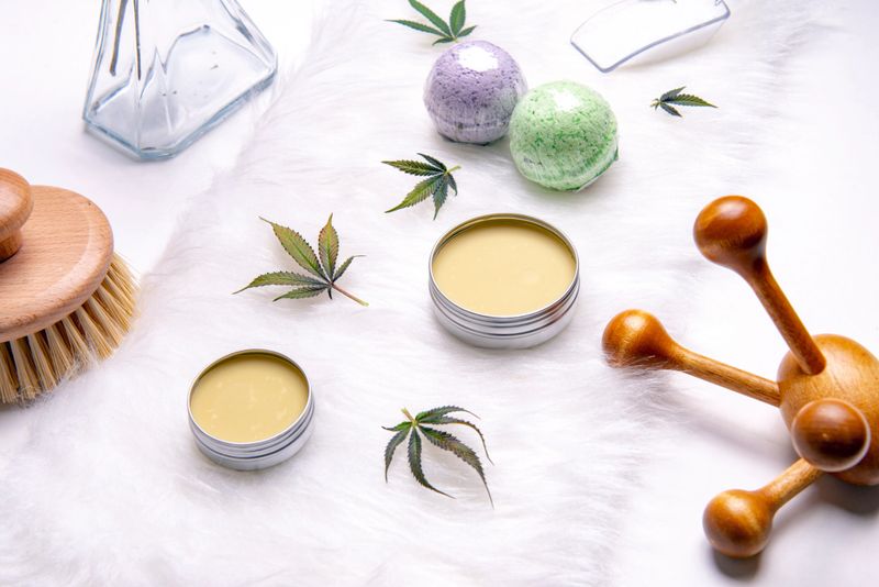 Assortment of cannabis topicals with bath bombs and marijuana salve isolated over white background - cannabis spa concept