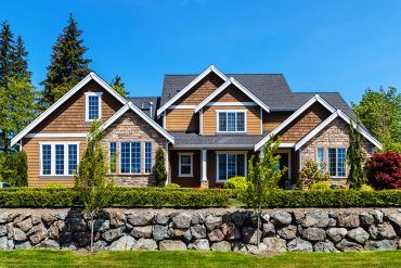 Modern suburban house with stone and wood exterior under blue sky.