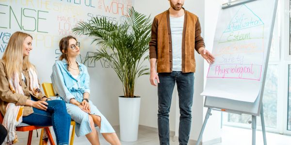 Man presenting on a flip chart to two women.