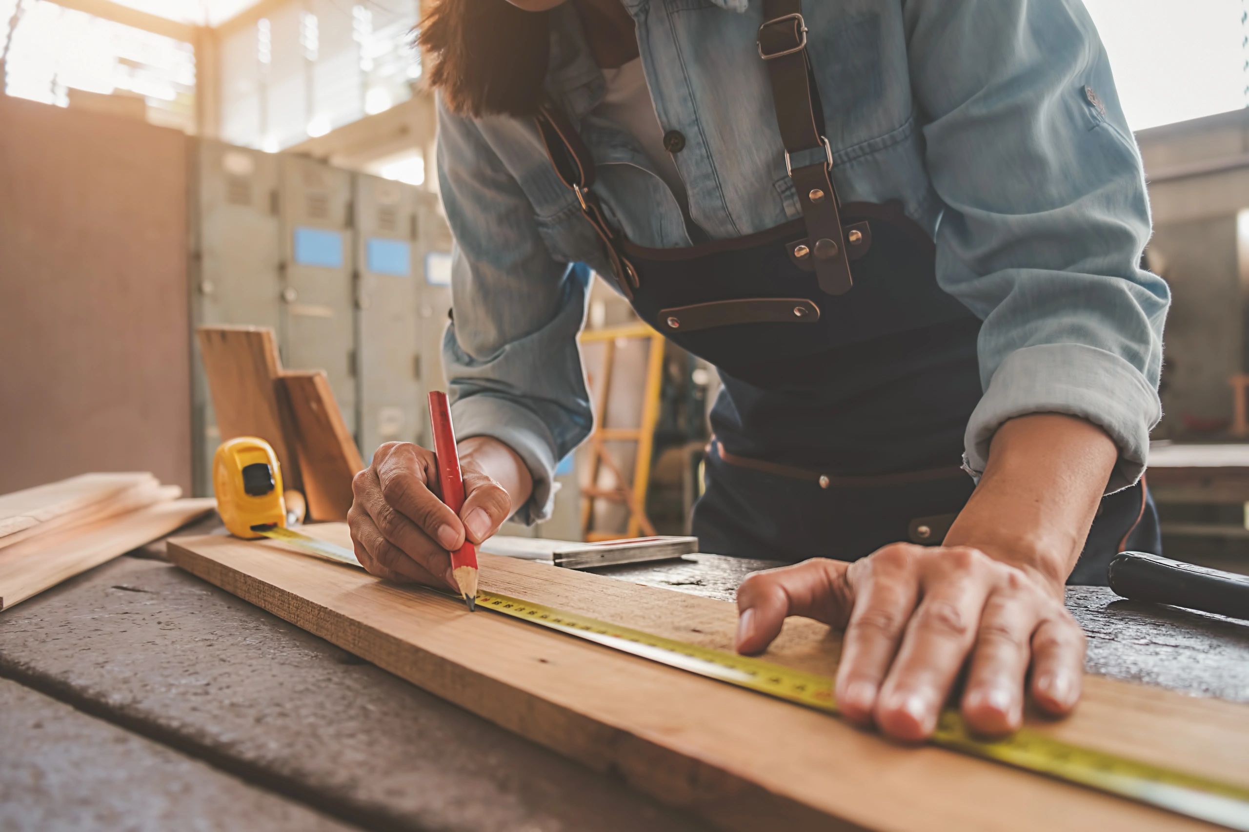 Man measuring and marking wood for carpentry work.