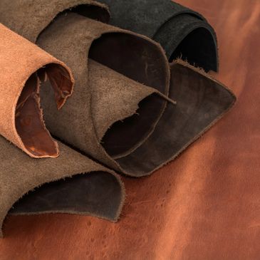 Close-up of rolled leather hides in various shades on a leather surface.