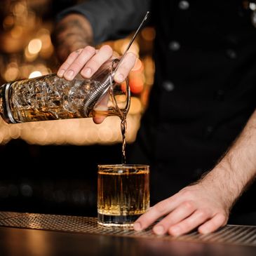 Bartender pouring whiskey into a glass.