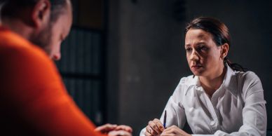 Woman interrogating a man in an orange shirt.