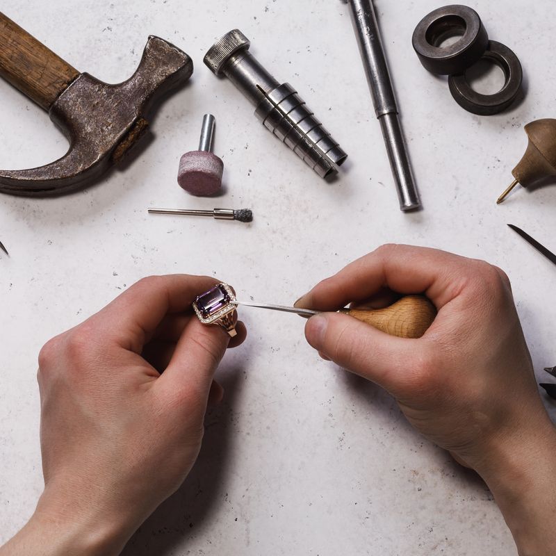 Jeweler fixes stones in a gold ring, top view