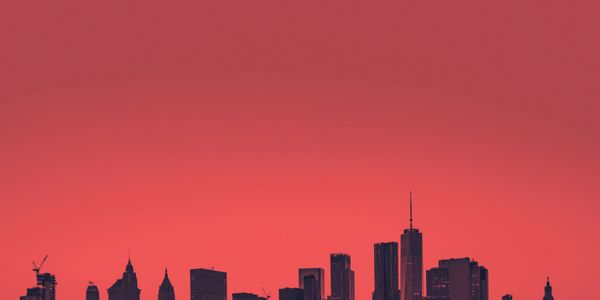 Silhouette of a city skyline against a vibrant red sky.