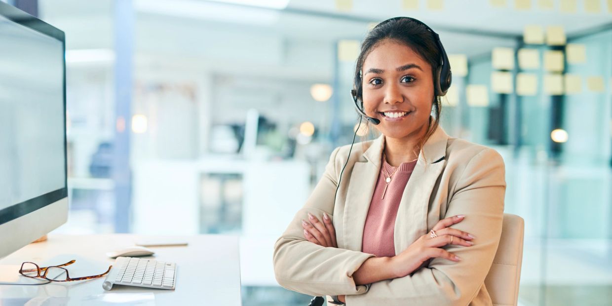 Smiling customer service representative wearing a headset at her desk.