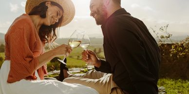 a man and a women looking at eachother smiling with wine glasses
