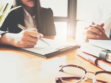 Two people discussing and taking notes in a bright office setting.