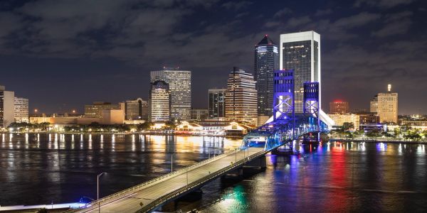 Night view of a city skyline with a lit bridge.
