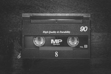 A black VHS tape labeled 'High Quality & Durability' on a wooden surface.