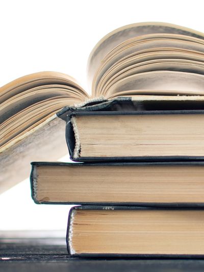 Stack of hardcover books with one open on top.