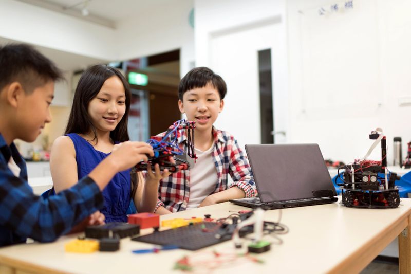 Group of young students working together on a robotic project in the school classroom.