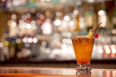 A tropical cocktail garnished with pineapple and cherry.