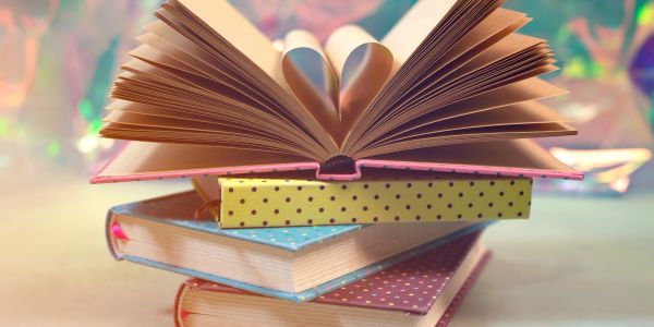 Open book pages folded into a heart shape on stacked polka dot books.