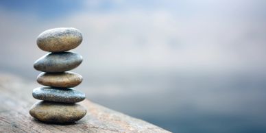 Stack of five smooth stones on a wooden surface with a blurred background.