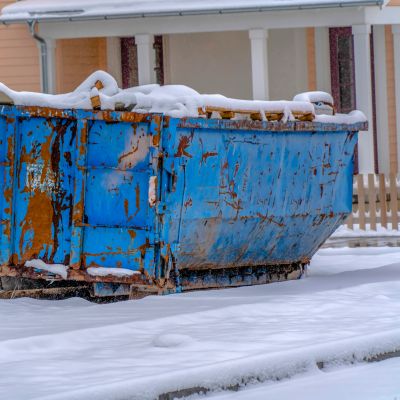 Rusty blue dumpster covered in snow.