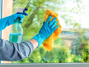 Person cleaning a window with spray and cloth.