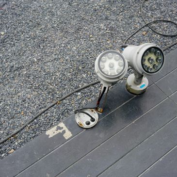Two outdoor LED spotlights on a stone surface.