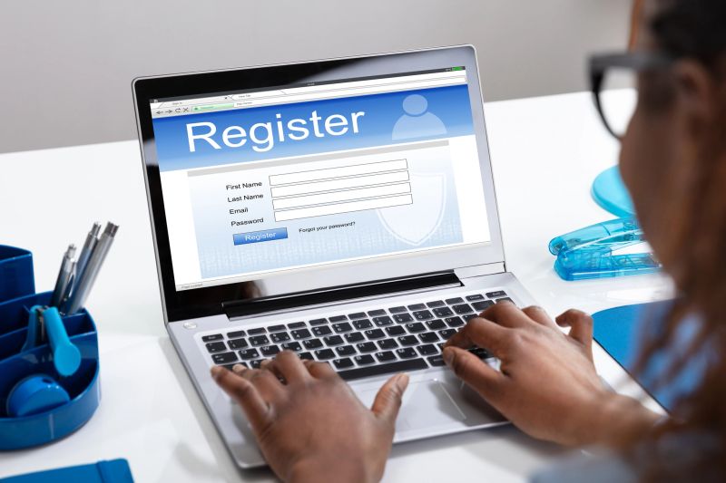 Businesswoman's Hand Filing Online Registration Form On Laptop In Office