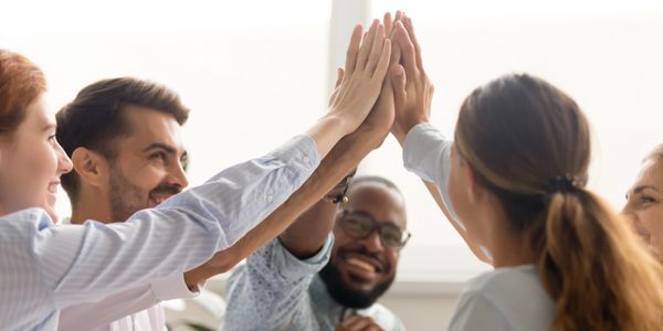 Diverse B2C personnel joined in a team high five, showcasing dedication and family values.