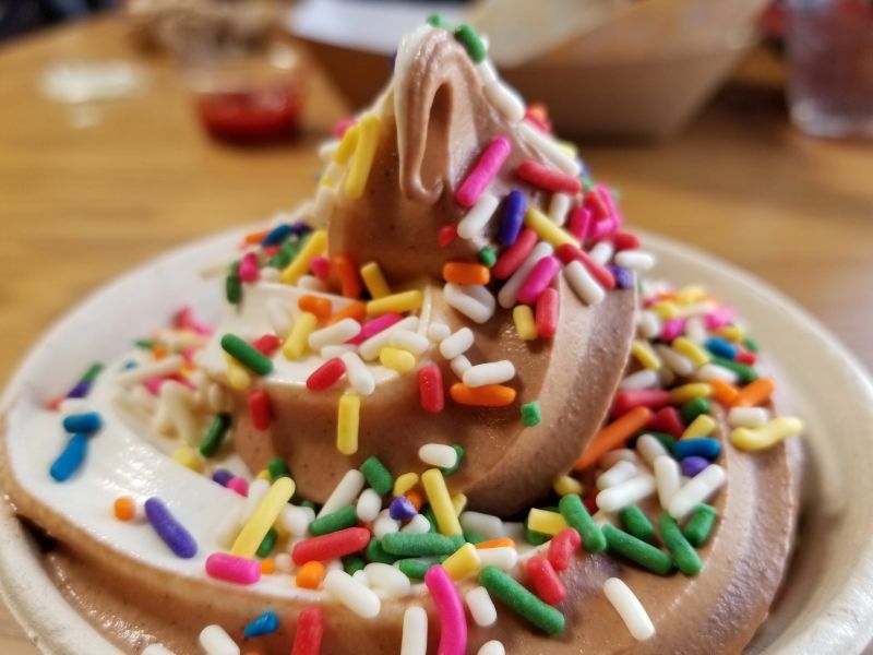 Close-up of swirl soft serve ice cream with chocolate and vanilla with rainbow sprinkles in a cup, February 21, 2018