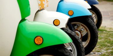 A close-up of colorful scooter fronts lined up outdoors.
