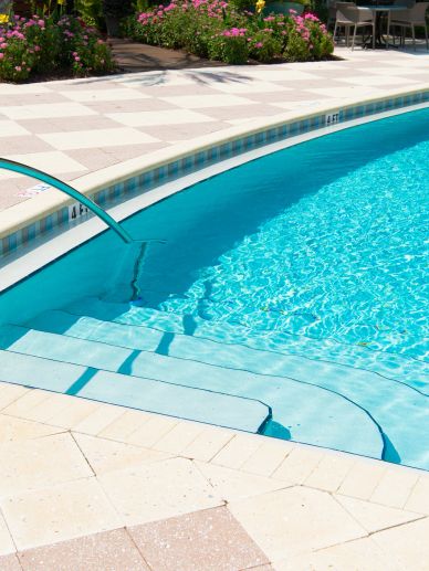 Clear blue pool water with tiled steps and surrounding flowers.