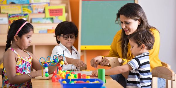 Teacher and children playing with educational toys in a classroom.